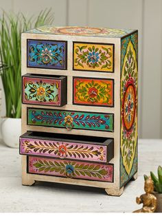 a multicolored wooden dresser with drawers and plants in the backgroung