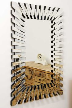 a mirror that is on the wall above a dresser with drawers and a clock in it