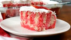 a piece of red velvet cake on a white plate with strawberries in the background