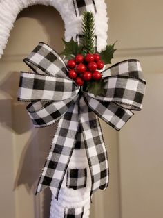 a white wreath with red berries and greenery hanging from the front of a door