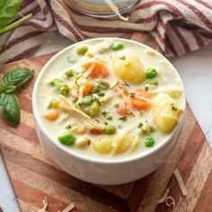 a white bowl filled with soup on top of a wooden cutting board