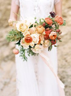 a woman holding a bouquet of flowers in her hand and wearing a white wedding dress