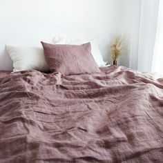 an unmade bed with pink sheets and pillows