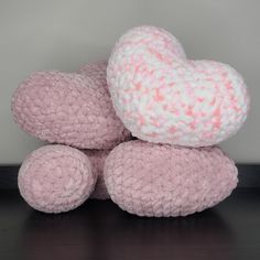 two pink and white teddy bears sitting next to each other on a wooden table with a gray wall in the background