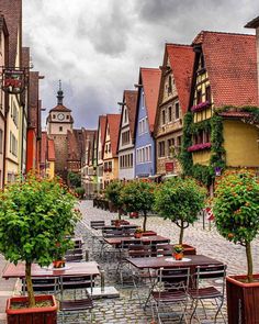 tables and chairs are lined up on the cobblestone street in an old european town