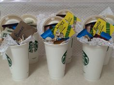 three starbucks coffee cups filled with different types of snacks and candy bar wrappers in them