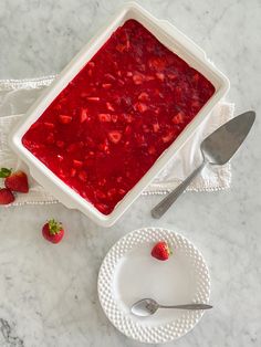 a white plate topped with strawberry sauce next to a bowl of strawberries