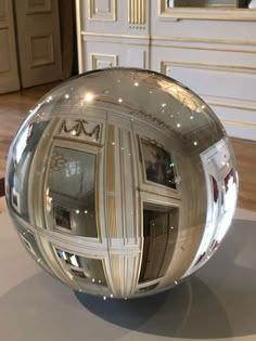 a silver ball sitting on top of a white table next to a mirror wallpaper