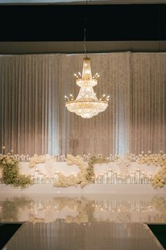 a chandelier hanging from the ceiling above a table with flowers and candles on it