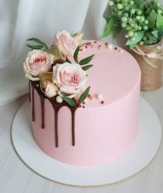 a pink cake with chocolate drips and flowers on top