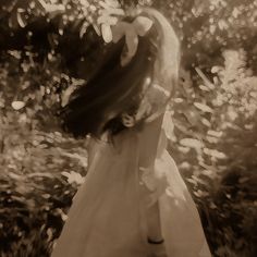 a woman in a white dress is walking through the woods