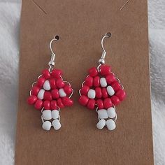 a pair of red and white beaded earrings sitting on top of a piece of cardboard