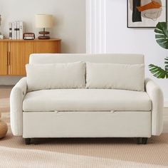 a white couch sitting in a living room next to a plant