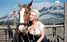 a woman sitting on the ground next to a horse