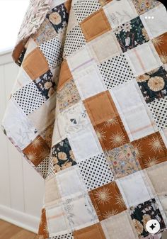 an orange and white patchwork quilt hanging on a wall next to a wooden floor