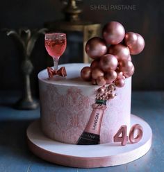 a birthday cake with a bottle of champagne and some ornaments on top, sitting on a table