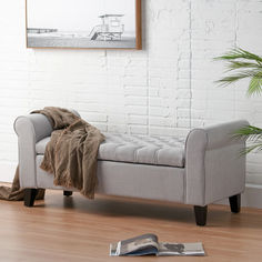 a couch with a blanket on it in front of a white brick wall and wooden floor