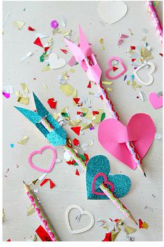 some paper hearts and other items on a table with confetti, streamers and scissors