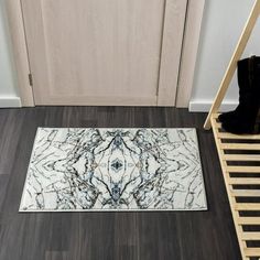 a white and blue rug sitting on top of a wooden floor next to a door