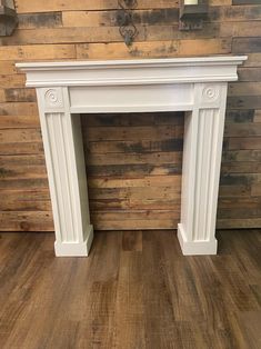 a white fireplace with wood paneling on the wall