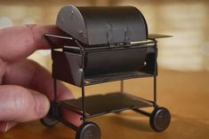 a hand is holding a miniature black cart