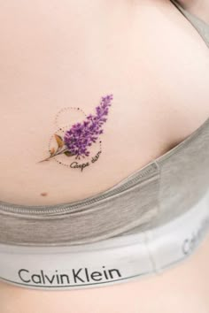 a woman's stomach with a small purple flower tattoo on her left side belly