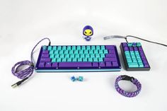 a purple and blue keyboard sitting on top of a white table next to a pair of headphones