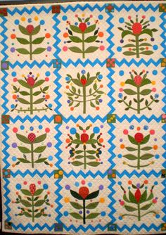 a blue and white quilt with colorful flowers on it's sides, in the center is