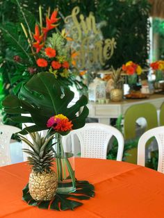 a pineapple sits on top of an orange tablecloth at a tropical themed party