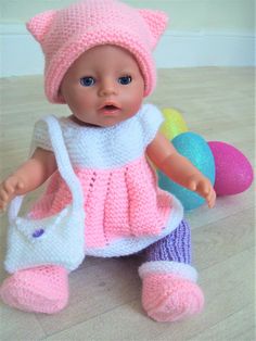 a baby doll wearing a knitted outfit and holding an easter egg in her hand