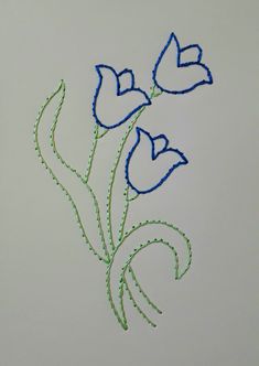 three blue flowers with green stems on a white surface, in the shape of hearts