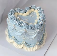 a blue frosted heart shaped cake sitting on top of a white tablecloth covered surface