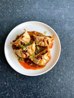 a white plate topped with dumplings covered in sauce