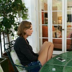 a woman sitting at a table with her legs crossed and talking to someone on the phone