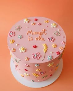 a pink cake decorated with flowers and words