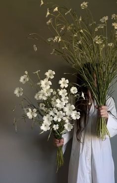 a woman is holding flowers in her hands