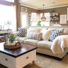 a living room filled with lots of furniture and pillows on top of a table in front of a window