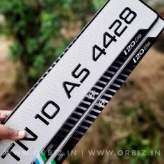 a person holding up a white and black street sign with numbers on it's sides