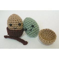 three crocheted toys sitting next to each other on a white surface, one has an egg and the other has two faces