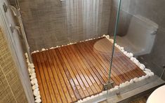 a bathroom with a wooden floor and glass shower door, next to a white toilet