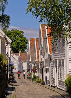 two people walking down a street lined with white houses