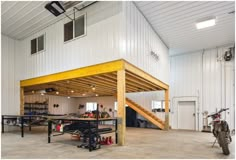 a garage with two motorcycles parked in front of it and stairs leading up to the second floor