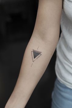 a woman's arm with a small triangle tattoo on the left side of her arm