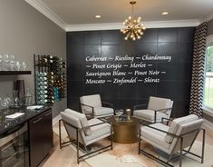 two chairs and a table in front of a black wall with wine glasses on it