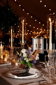 the table is set with silverware, candles and flowers in vases on it