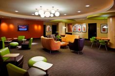 a room with chairs, tables and televisions inside of it that is decorated in green and brown colors