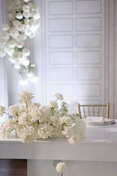 white flowers are sitting on the table in front of a chandelier