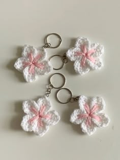 four crocheted flower keychains with pink and white flowers on them, sitting on a table