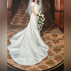 a woman in a white wedding dress holding a bridal bouquet and posing for the camera