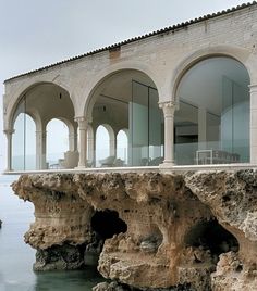 a large building sitting on top of a cliff next to the ocean with arched windows